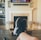 A person is relaxing in a living room with feet up on a wooden table. A TV mounted above a fireplace is displaying a popular streaming platform. Shelves on either side of the fireplace hold decorative items. A smartphone can be seen on the table.