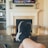 A person is relaxing in a living room with feet up on a wooden table. A TV mounted above a fireplace is displaying a popular streaming platform. Shelves on either side of the fireplace hold decorative items. A smartphone can be seen on the table.