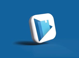 A 3D icon with a play button symbol and a book graphic is centered against a solid blue background. The icon is designed in white and shades of blue, with a modern and sleek appearance.